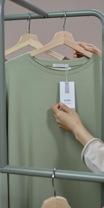 Close-up of a hand checking a price tag on a t-shirt in a minimalist clothing store.