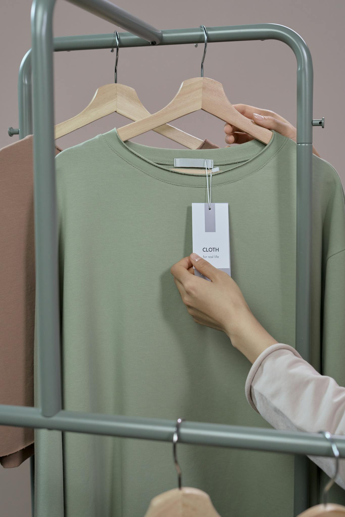 Close-up of a hand checking a price tag on a t-shirt in a minimalist clothing store.