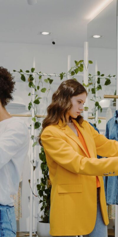 Two women shopping in a trendy clothing store, browsing stylish outfits.